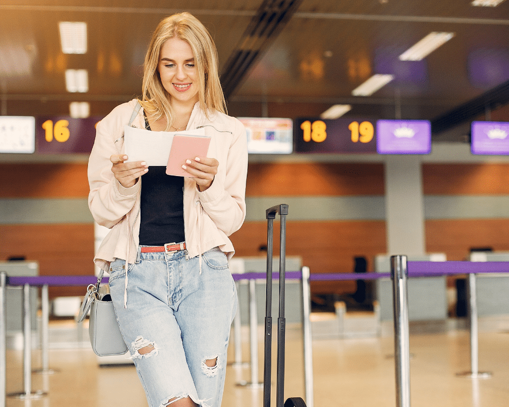 تصویر زنی در فرودگاه ایستاده است که ویزا در دست دارد.